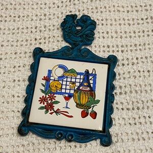 vintage collectible kitchen trivet with a ceramic tile set in a cast iron frame